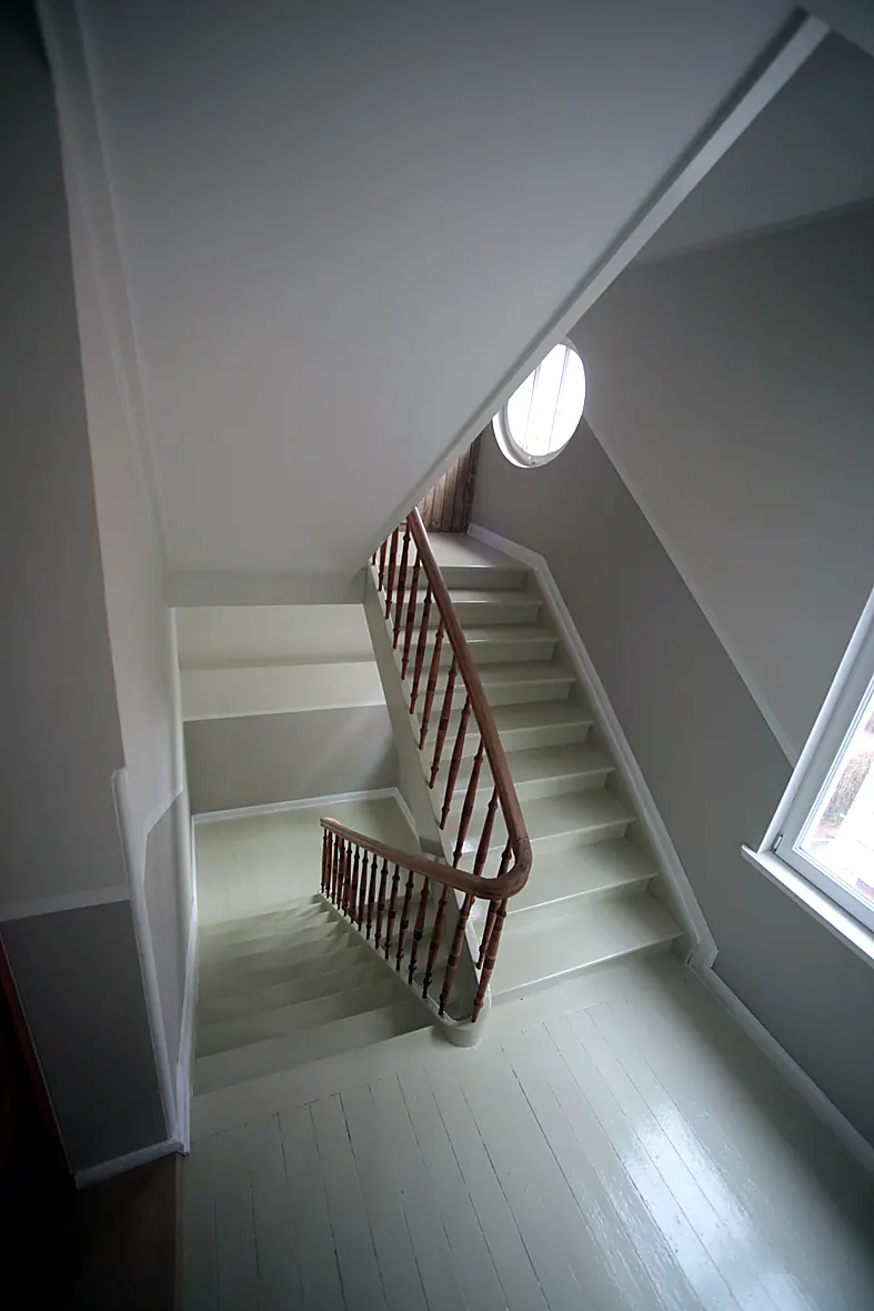 Helle Ateliertreppe im Dachgeschoss der Villa Valentino mit gedrechseltem Geländer und rundem Ochsenauge-Fenster