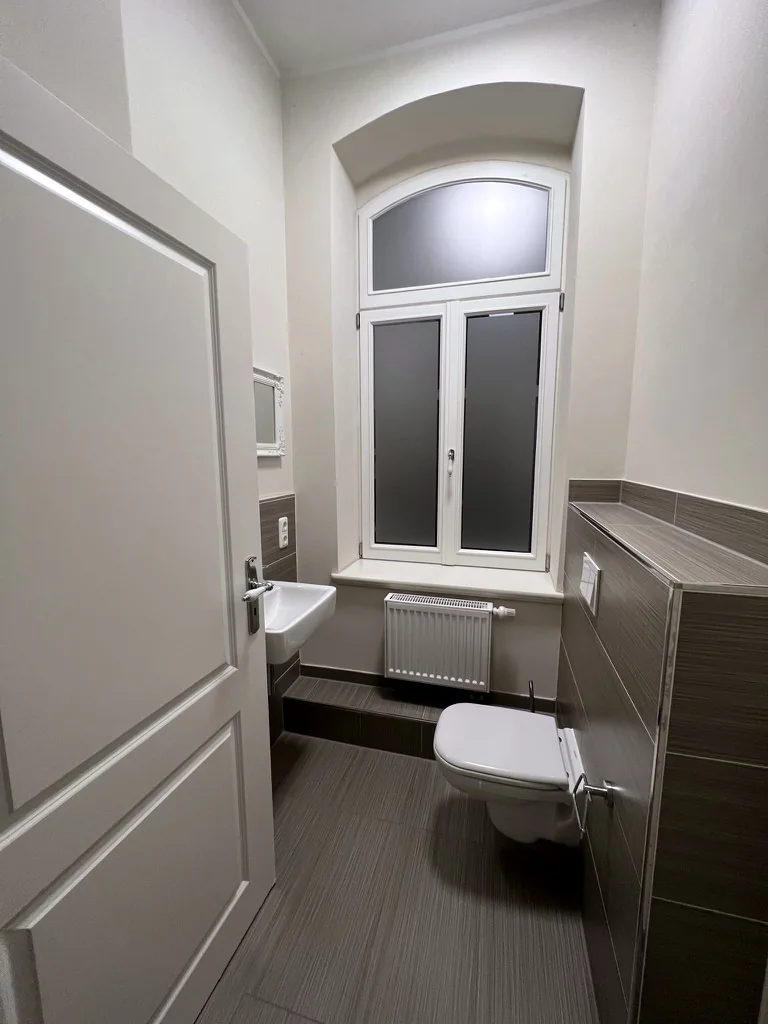Gäste-WC der Villa Valentino mit dunklen Wandfliesen, wandhängendem WC und Fenster