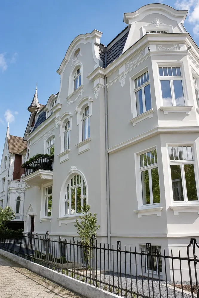 Villa Valentino in Bad Oeynhausen vor blauem Himmel – Gesamtansicht der sanierten Fassade mit Stuck und Balkon