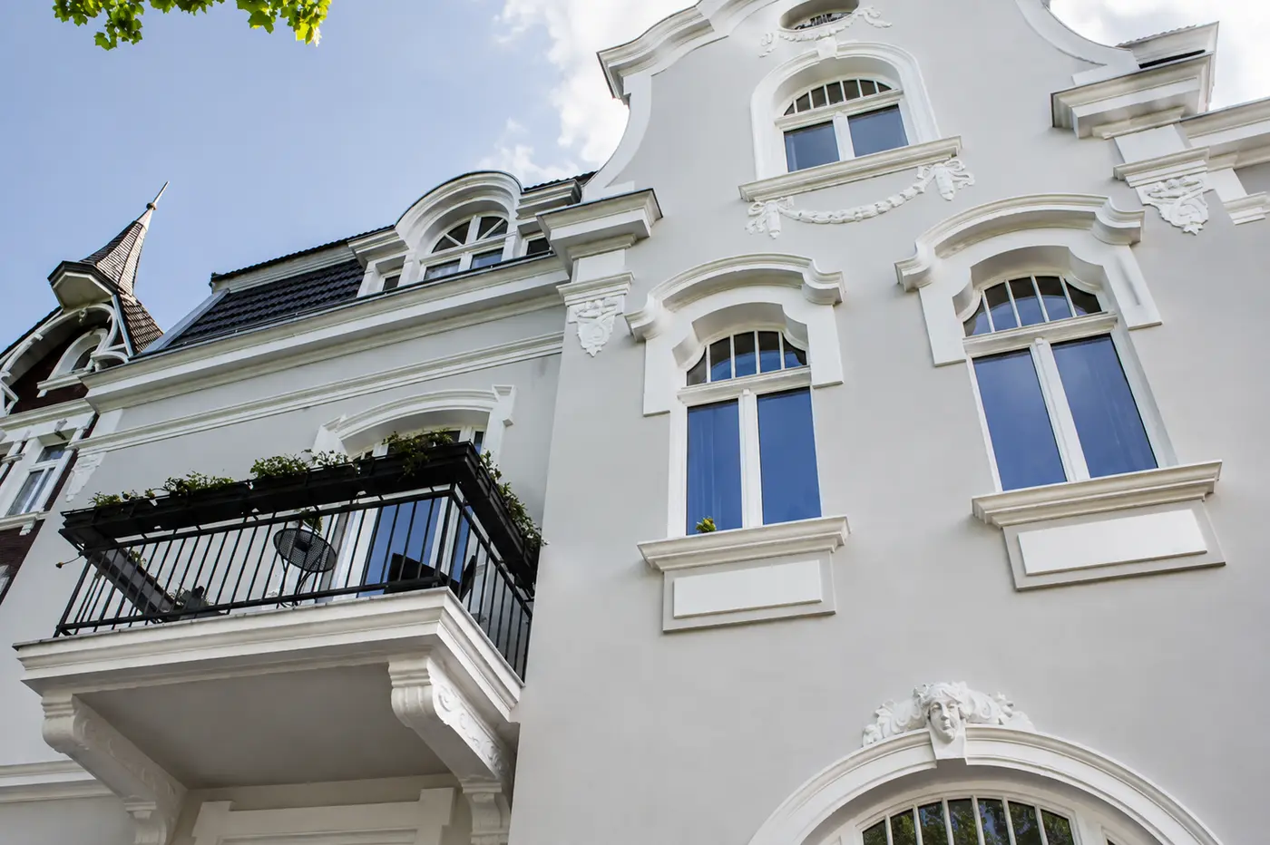 Fassadendetail der Villa Valentino – Schweifgiebel, Stuckgirlanden und denkmalgerechte Holzfenster im Untersichtblick