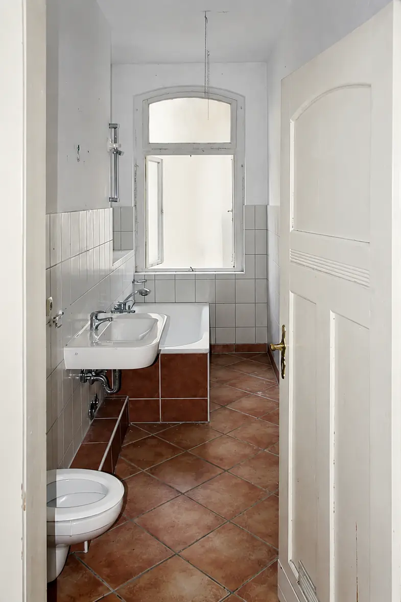 Das alte Bad der Villa Valentino vor der Sanierung mit weißen Fliesen und Terracotta-Boden