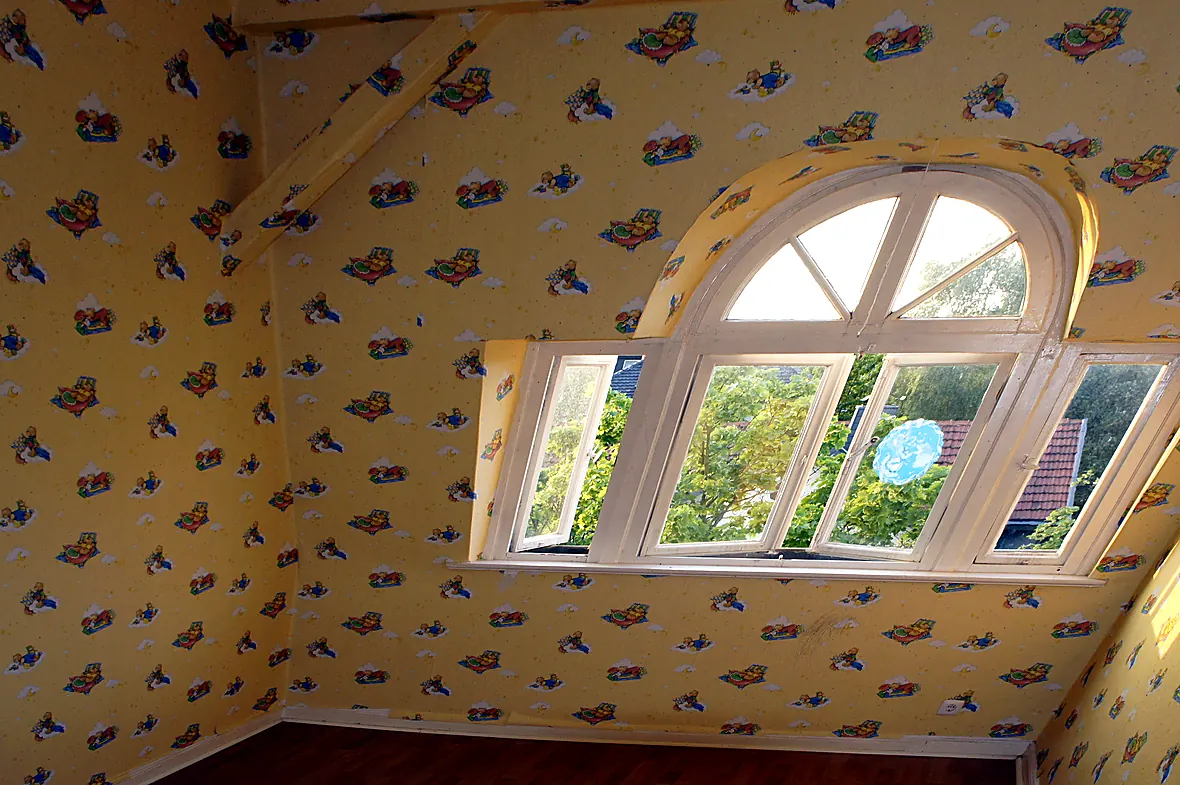 Kinderzimmer unter dem Dach der Villa Valentino vor der Sanierung mit gelber Teddybär-Tapete